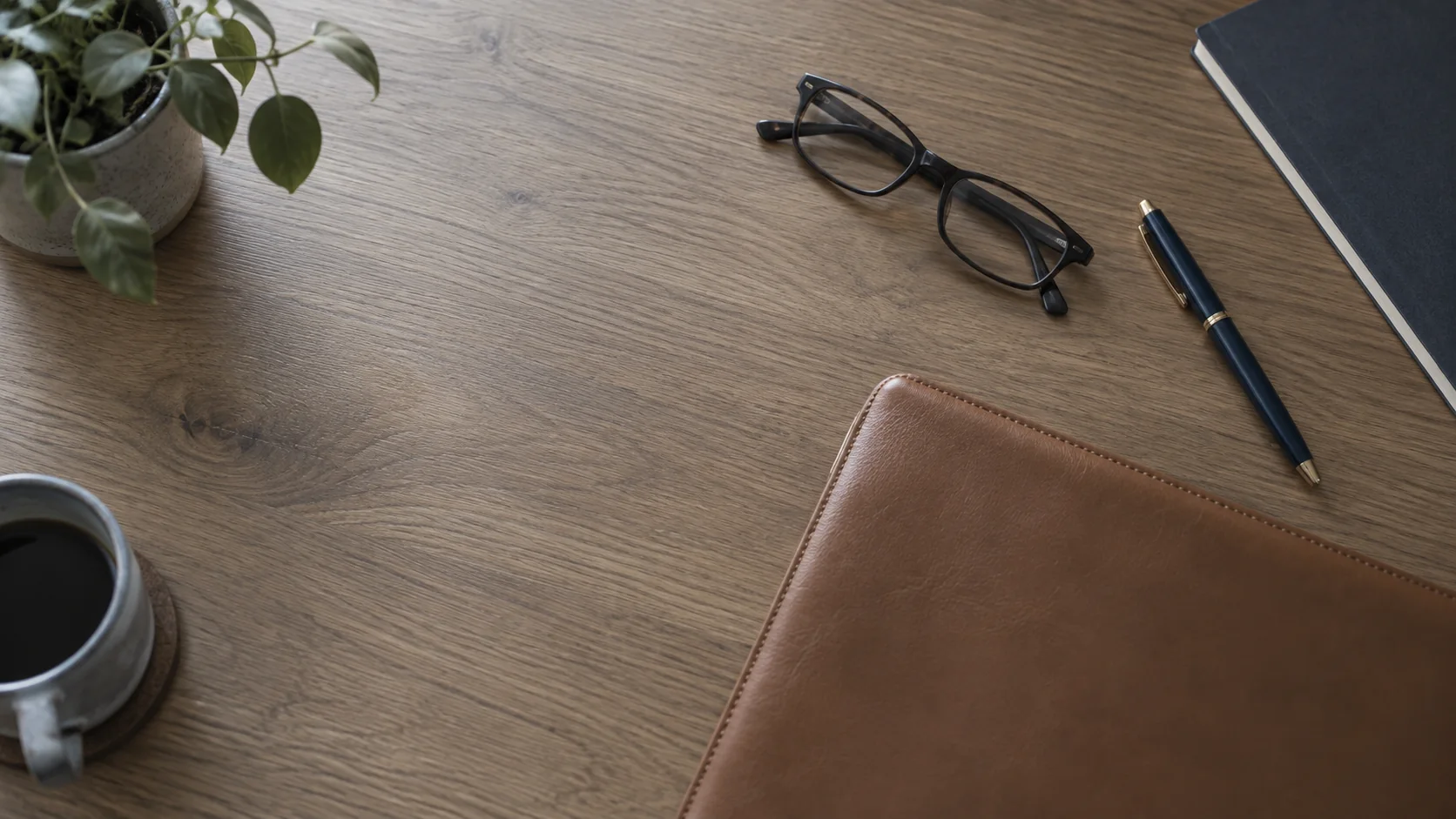 A desk in the Renna & Associates office with a leather folder, reading glasses and a pen